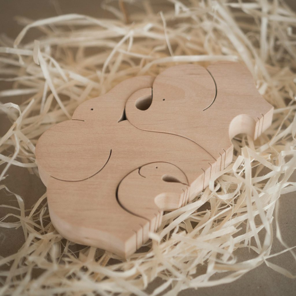 Rustic wooden elephant puzzle toy surrounded by straw, showcasing artisan craftsmanship.