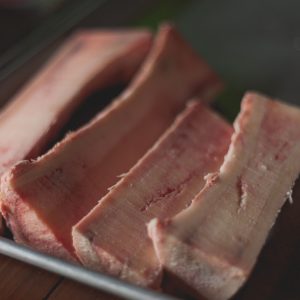 High-quality close-up image of raw beef bone marrow slices on a tray, perfect for cooking concepts.